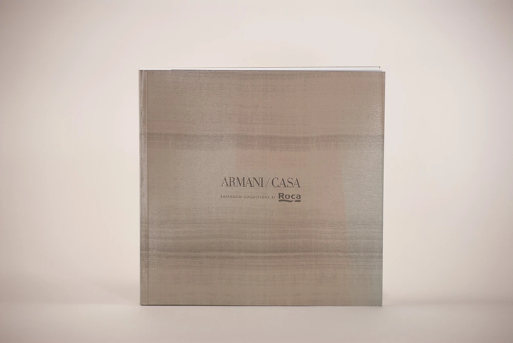 Cubierta del catálogo Armani 2024 con un acabado que imita la textura de un papel exclusivo de decoración. La impresión utiliza tintas metalizadas y un acabado gofrado que resalta la calidad y el lujo característicos de la marca.