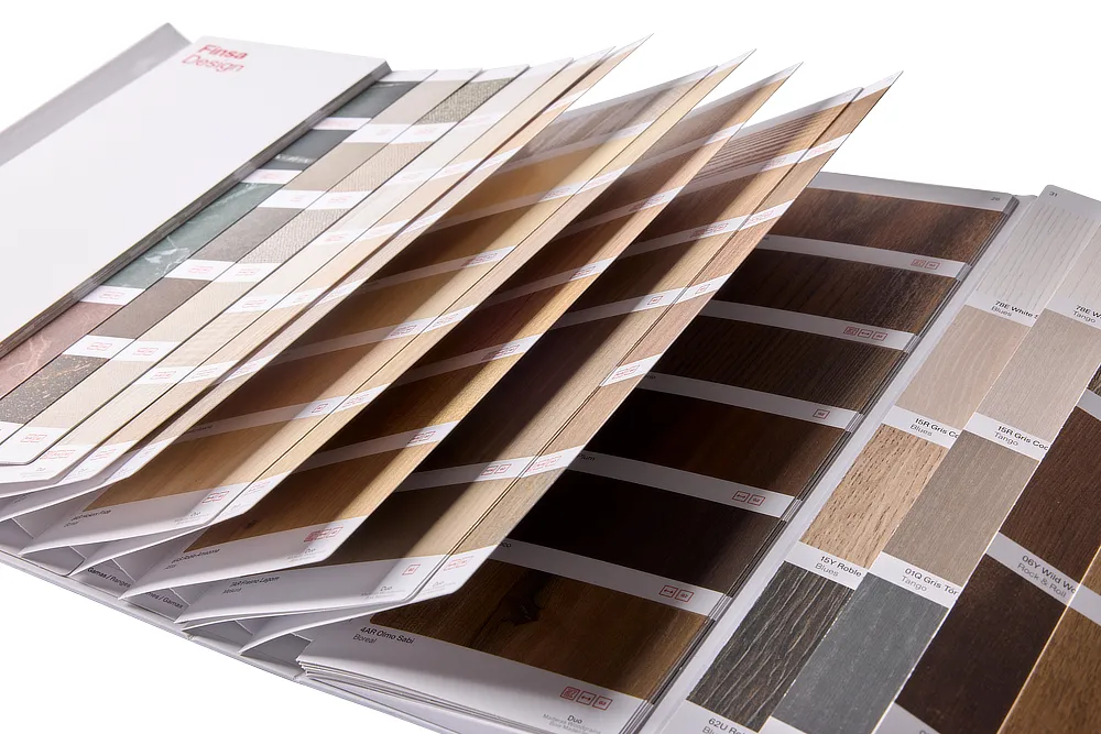 Muestrario de catálogo Finsa desplegado, con amplia selección de muestras de madera y superficies decorativas en distintos tonos y texturas."