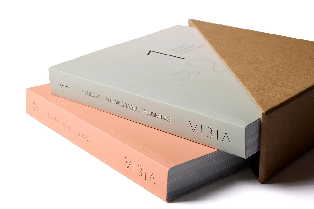 Catálogos de producto Vibbia con diseño minimalista, cubiertas en tonos pastel y packaging personalizado, mostrando una cuidada presentación premium.