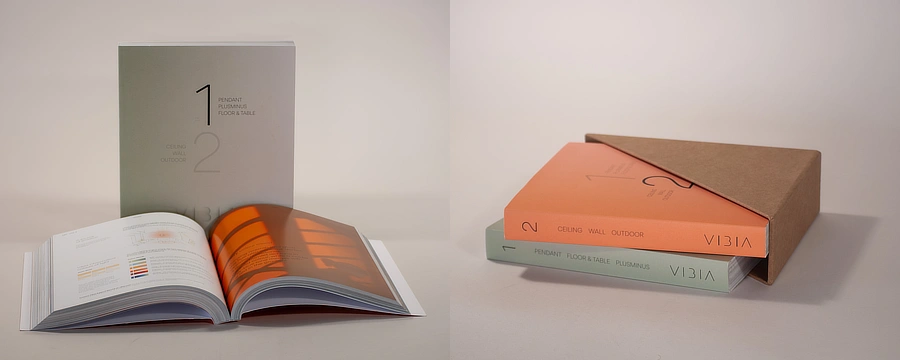 Dos catálogos impresos de diseño premium, uno abierto y otro en su caja kraft personalizada, con portadas limpias y acabados cuidados.
