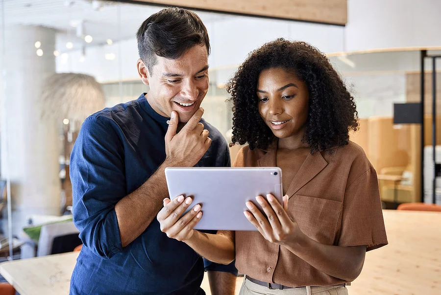 Dos profesionales observan un catálogo digital en una tableta, ilustrando el uso colaborativo de herramientas interactivas en el proceso comercial.
