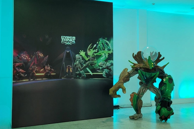 Escenografía inmersiva con personaje corpóreo a tamaño real para la promoción del videojuego Cyber Titan, con fondo gráfico iluminado.