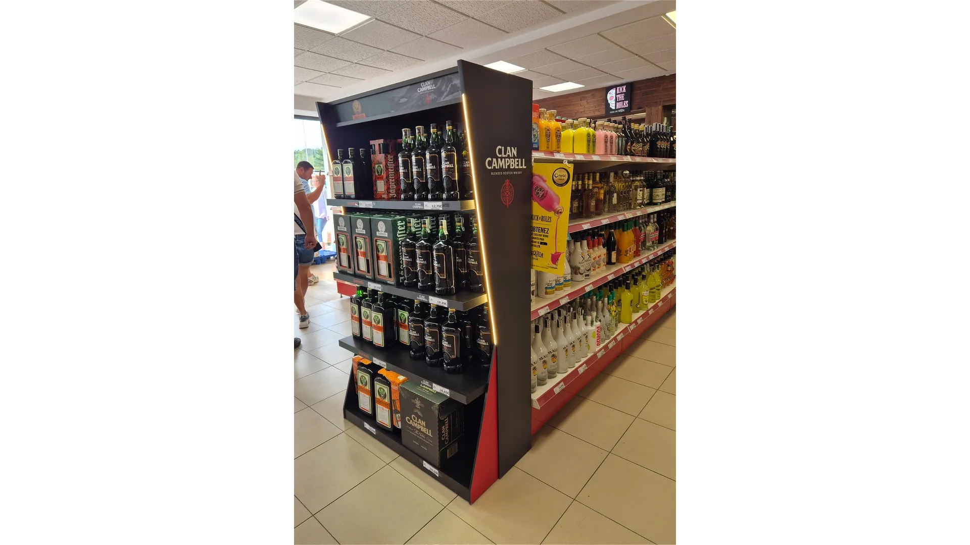 Vista lateral derecha de la cabecera de PLV renovable para Great Spirit, con iluminación LED, botellas expuestas y estantes llenos en un supermercado.