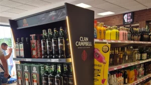 Top detail of the renewable POS header for Great Spirit, with vertical LED lighting and highlighted Clan Campbell bottles at the point of sale.