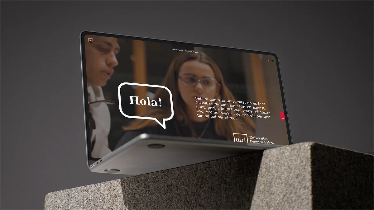 Pantalla inclinada de dispositivo mostrando saludo inicial del catálogo digital de la UPF, con fotografía de estudiantes y mensaje de bienvenida sobre fondo oscuro.