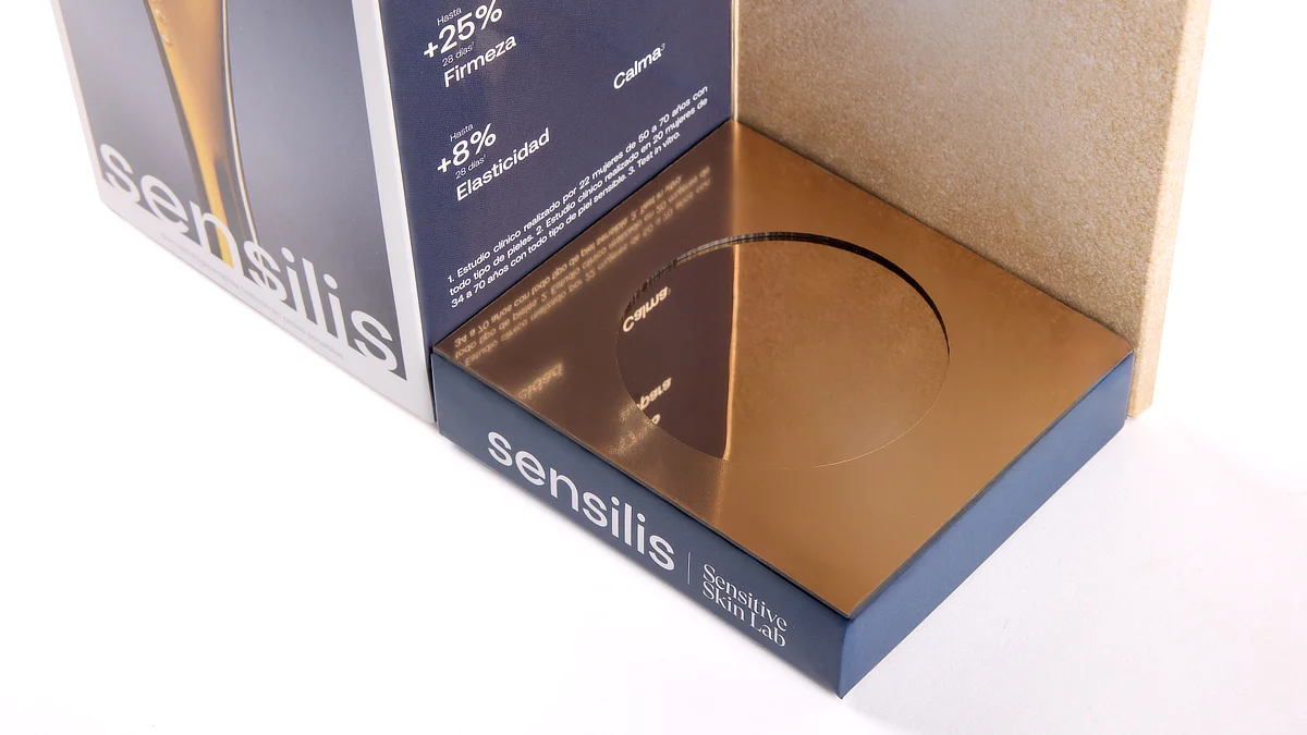 Detalle del área inferior del expositor de Sensilis, con superficie dorada reflectante y espacio específico para la colocación del frasco del producto.