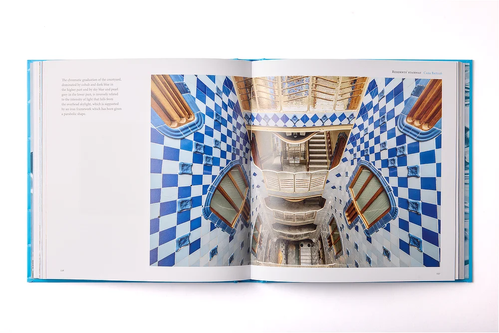 Doble página del libro de arte Casa Batlló que muestra una fotografía del patio de luces con su característica degradación cromática de azulejos azules.