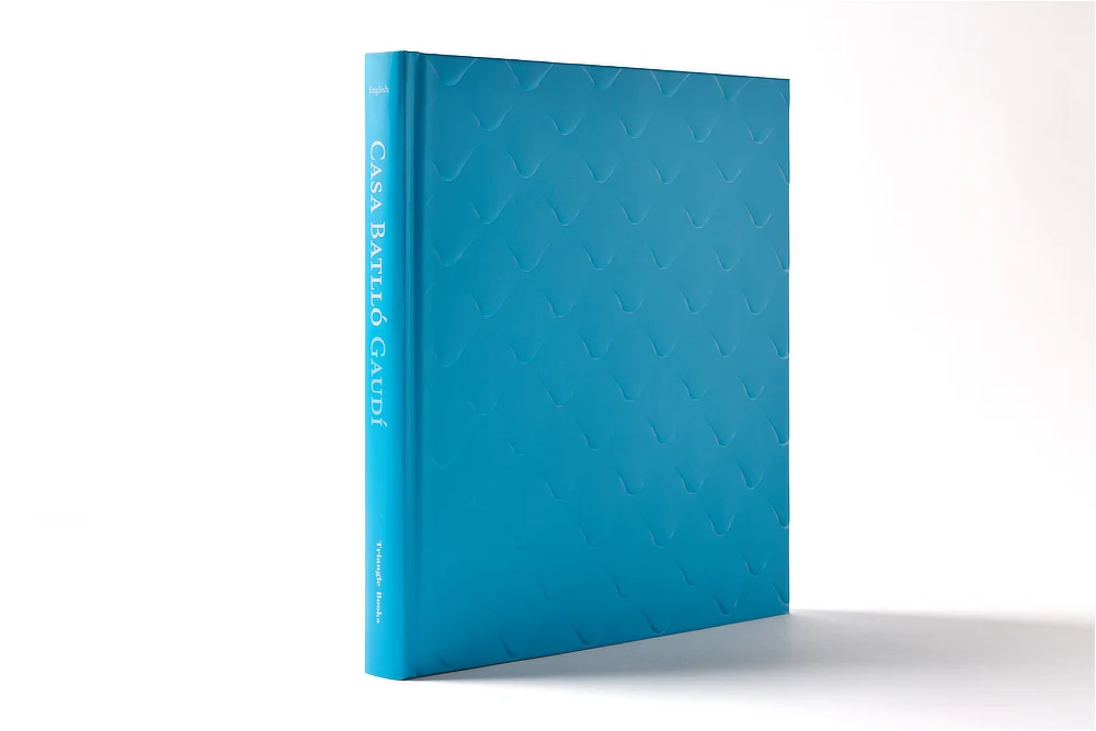 Vista en perspectiva del libro de arte Casa Batlló mostrando el lomo redondo con el título impreso y la textura tridimensional de la portada.