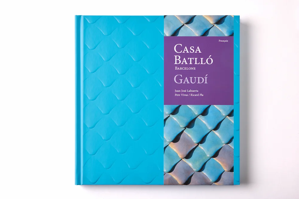 Edición en francés del libro de arte Casa Batlló, identificada por una faja vertical de color púrpura sobre la característica cubierta con relieve azul.