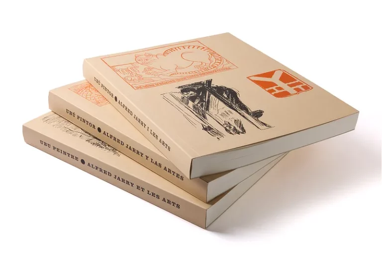 Tres exemplars del llibre d'art Alfred Jarry apilats, mostrant els lloms en català, castellà i francès sobre un fons blanc net.