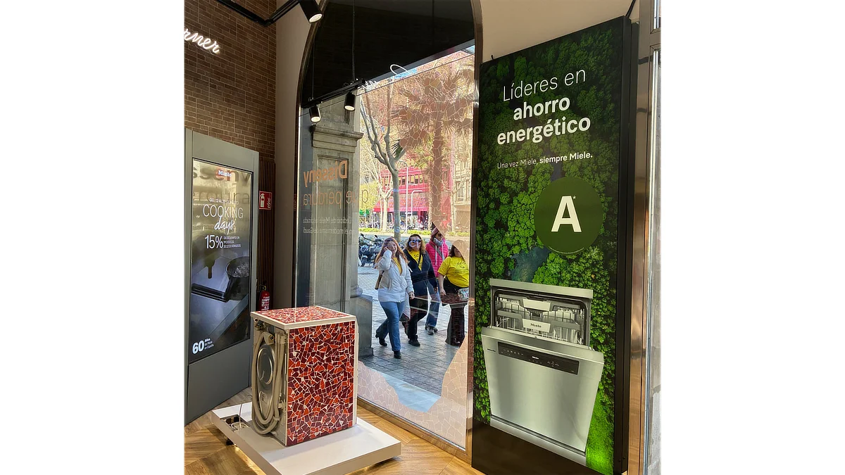 Lavavajillas Miele integrado en una plataforma de césped artificial frente a un panel gráfico con la imagen de un bosque y el mensaje Líderes en ahorro energético.