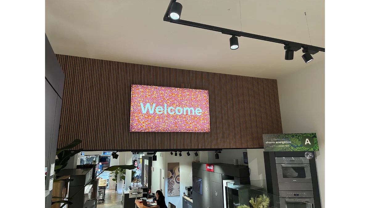 Interior de tienda Miele con una caja de luz superior que muestra el mensaje Welcome sobre un fondo de mosaico en tonos cálidos.