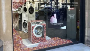 Lavadora Miele con vinilo decorativo inspirado en el mosaico de Gaudí situada en un escaparate con gráfica de comunicación sobre ahorro energético.