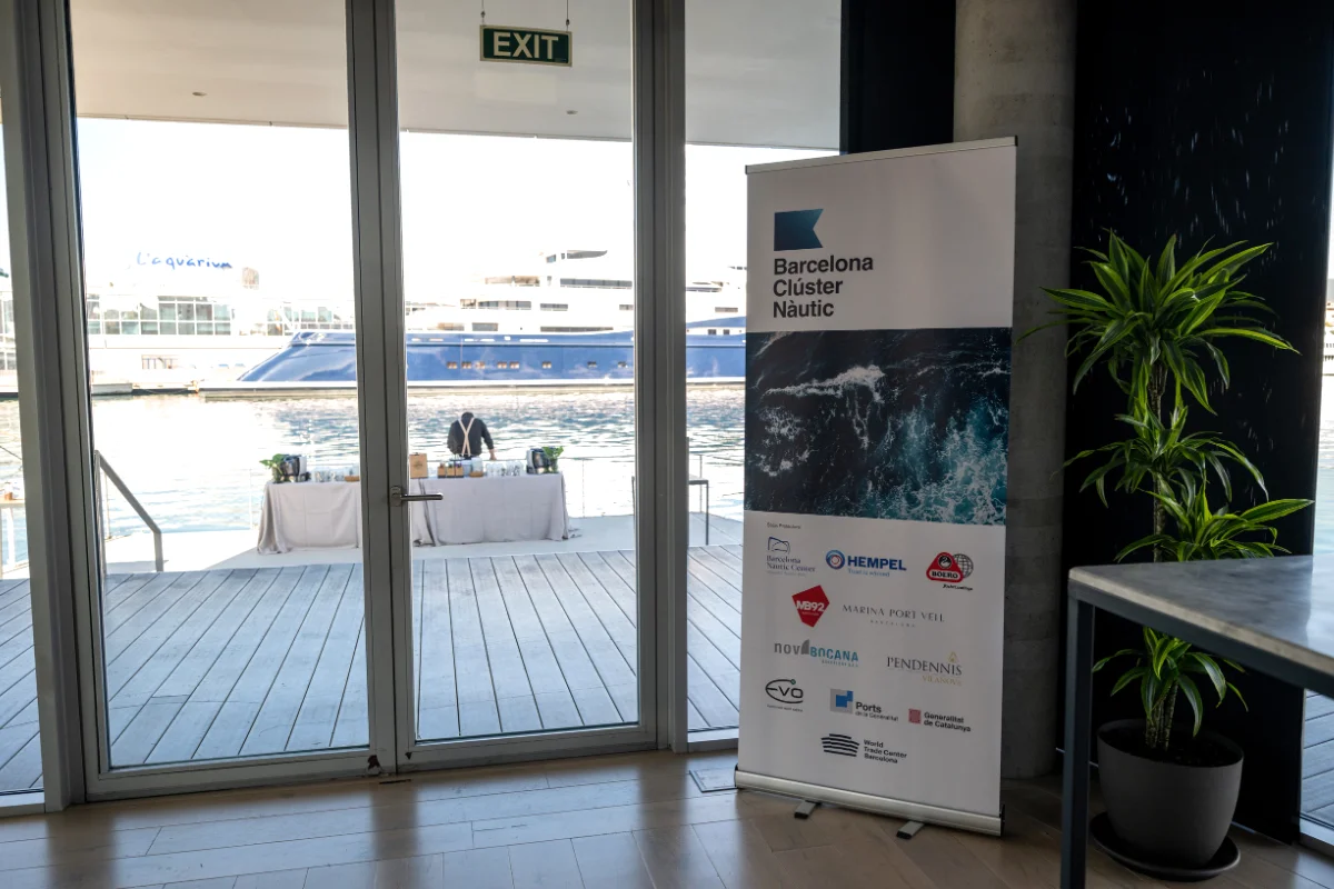 Roll-up de gran formato Barcelona Nautical Summit situado junto a acceso exterior con vistas al puerto, combinando señalización, branding y contexto náutico del evento.