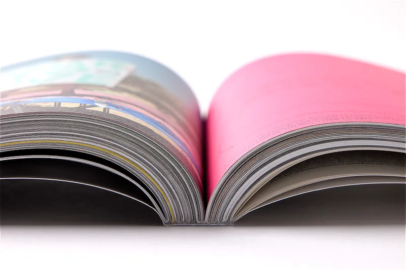Detalle en primer plano de la encuadernación técnica de un libro de fotografía profesional abierto, mostrando el lomo y el grosor de las páginas impresas.
